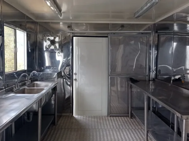 Interior de cocina en acero inoxidable con mesones y lavaplatos